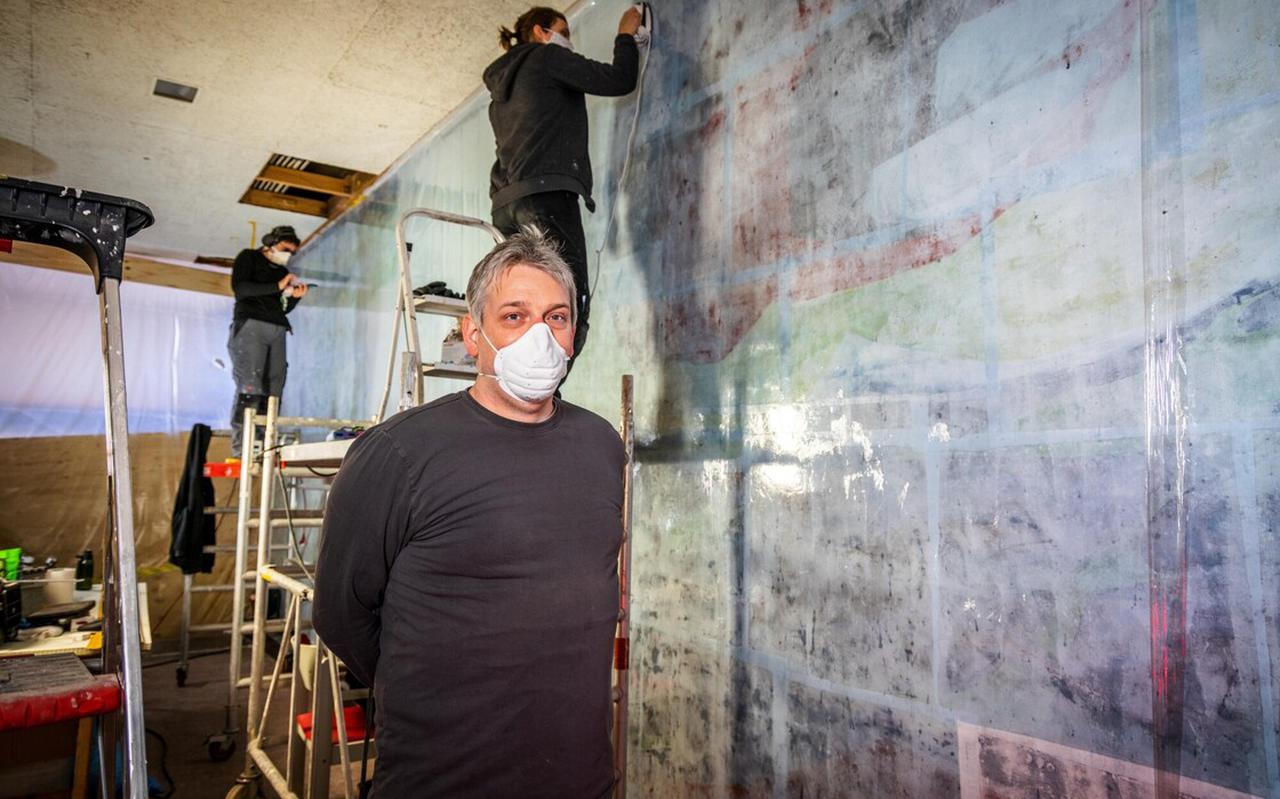 Restaurateur Fabian Rasson voor de muurschildering, die nu in Zeeland ligt om gerestaureerd te worden.