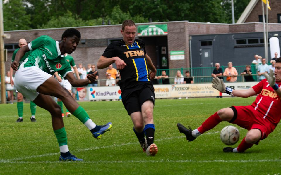 Junior Miguel schiet de bal onder keeper Stefan Kortman van FC Ommen door: 2-1.
