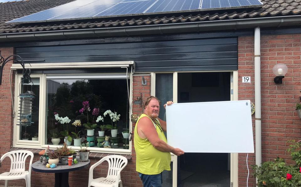 Okke Panneman met één van zijn infraroodpanelen. Op het dak liggen zonnepanelen.