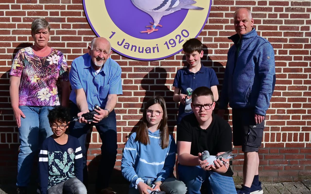 De vier jeugdleden van PV De Valk poseren samen met hun duiven en hun begeleiders.