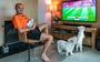 Oranjefan Hans Noppers poseert met zijn pasgeboren zoontje Finn op schoot. Ook zijn twee hondjes zijn fanatiek voetbal aan het kijken.