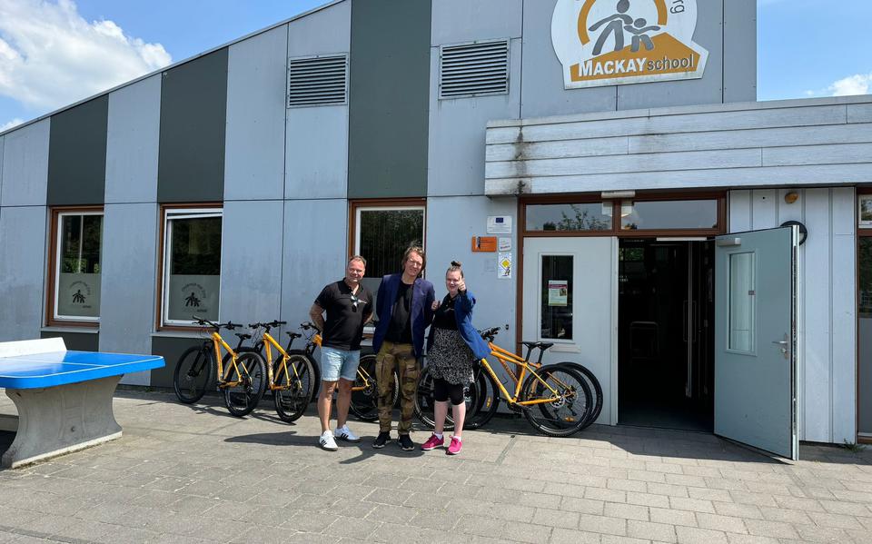 Eigenaar Edwin Mulder en dochter Nikki overhandigen de mountainbikes aan de directeur van de Mackayschool Ronald Kamerman.