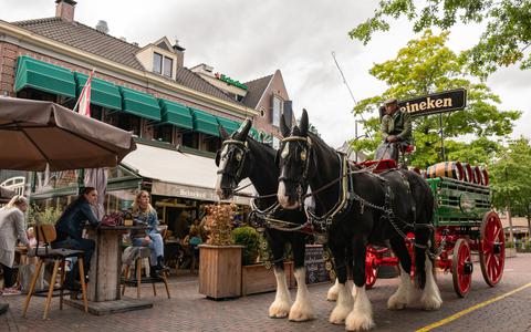 Twee paarden met daarachter een traditionele bierkar lopen die zondag door de stad. 